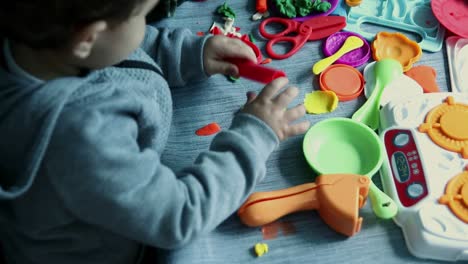 child playing with pasticine dough and asorted acessories