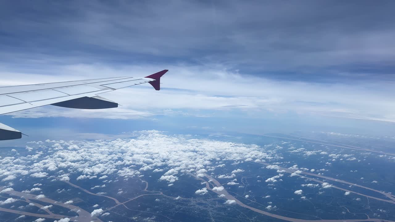 View from airplane window over clouds and rivers, peaceful flight scene