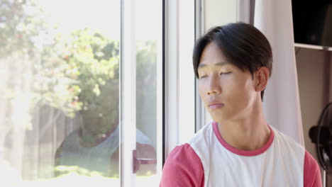 looking out window, young asian man in casual shirt reflecting in bright room, copy space
