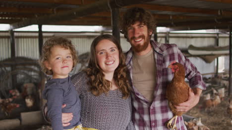 portrait of smiling caucasian family holding chicken, looking at camera