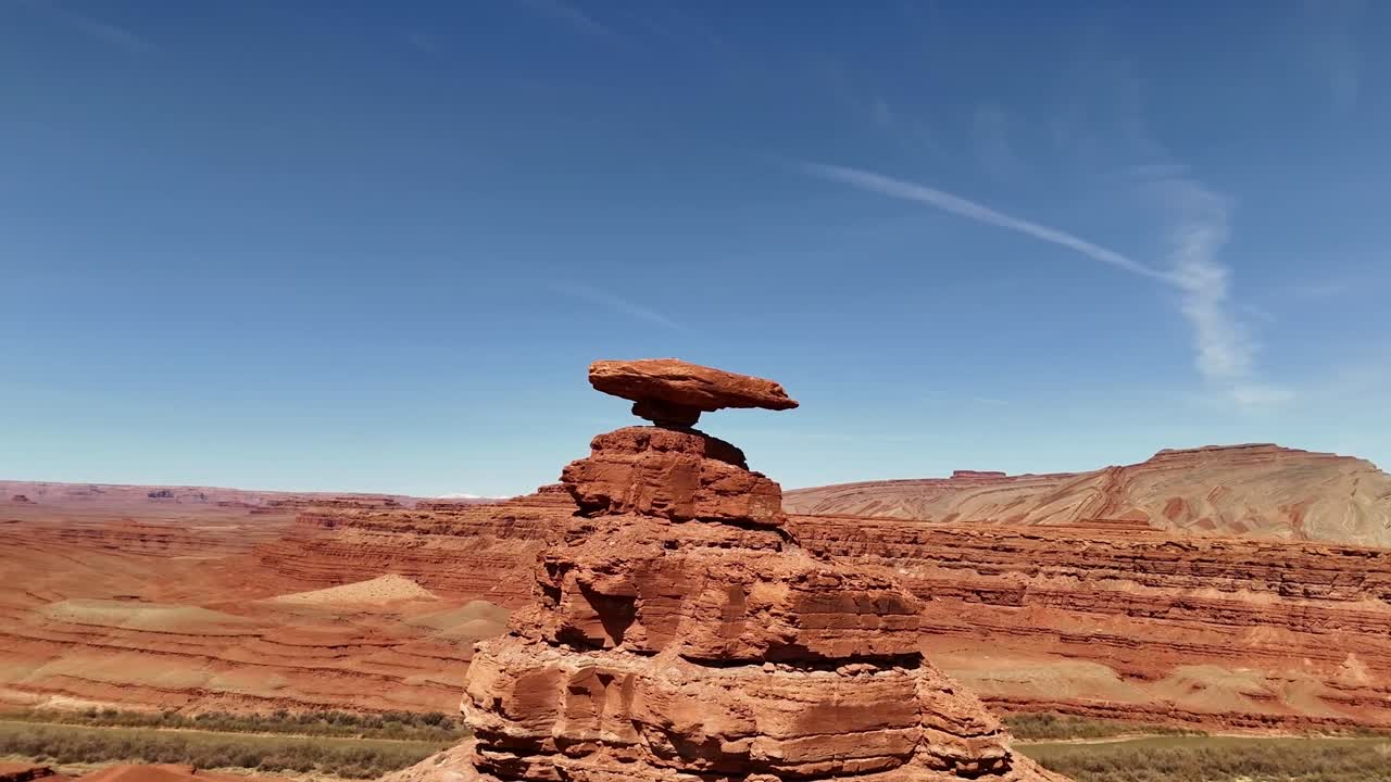 Mexican Hat Rock in Utah. Drone slowly orbiting, red cliffs with blue skies in southeastern Utah