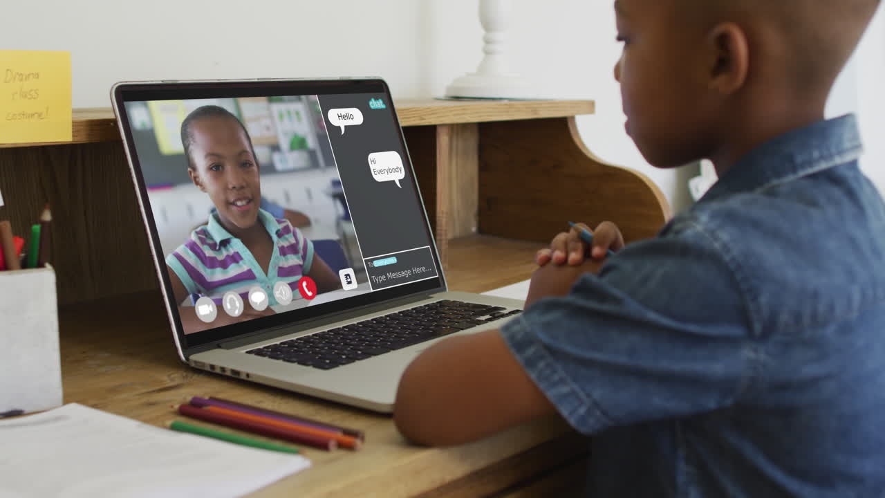 Schoolboy using laptop for online lesson at home, with his colleague and web chat on screen