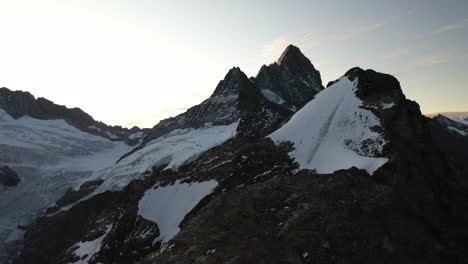 tomas de drones panorámicas de izquierda a derecha, revelando los picos de las montañas, las cimas y las empinadas laderas cubiertas de nieve y hielo del glaciar