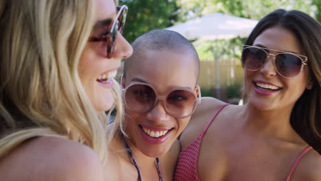 group of smiling female friends outdoors relaxing and enjoying summer pool party