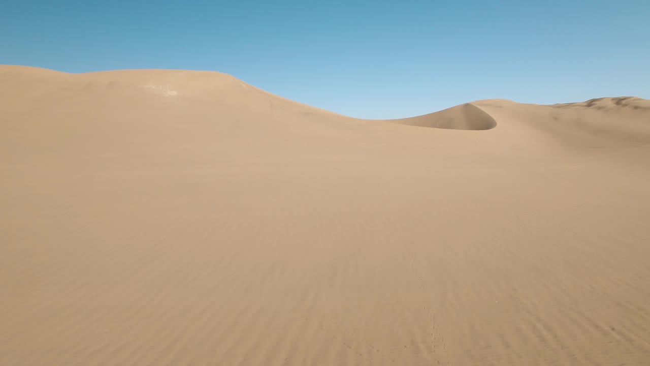 vista aérea de personas de pie sobre una gran duna del desierto en huacachina, perú