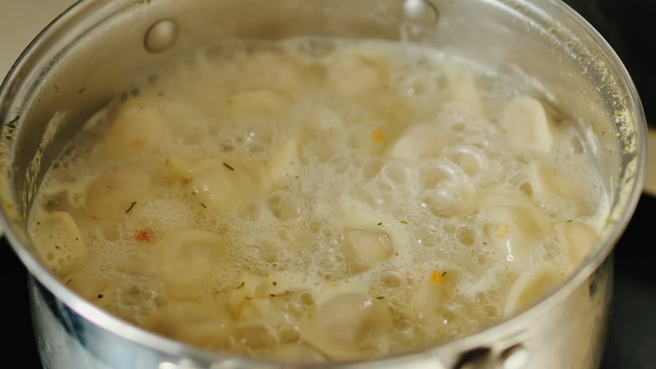 Primo piano di ravioli che galleggiano in un brodo fumante e gorgogliante durante una leggera bollitura