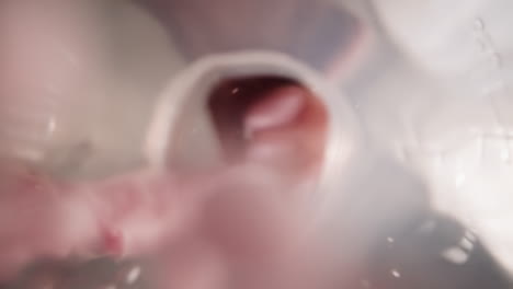 lady hand pours bright edible balls into water in bottle