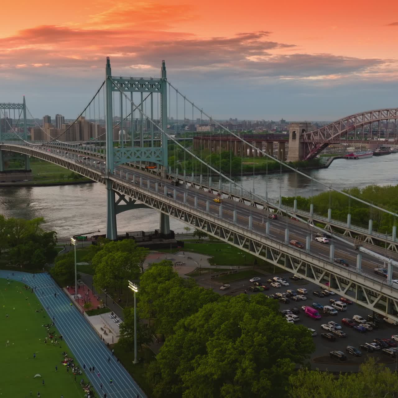 Splendid scenery of the bridges over the narrow river. Parking lot and stadium locating under nearby Robert F. Kennedy bridge. Cityscape at backdrop of pink-blue sky