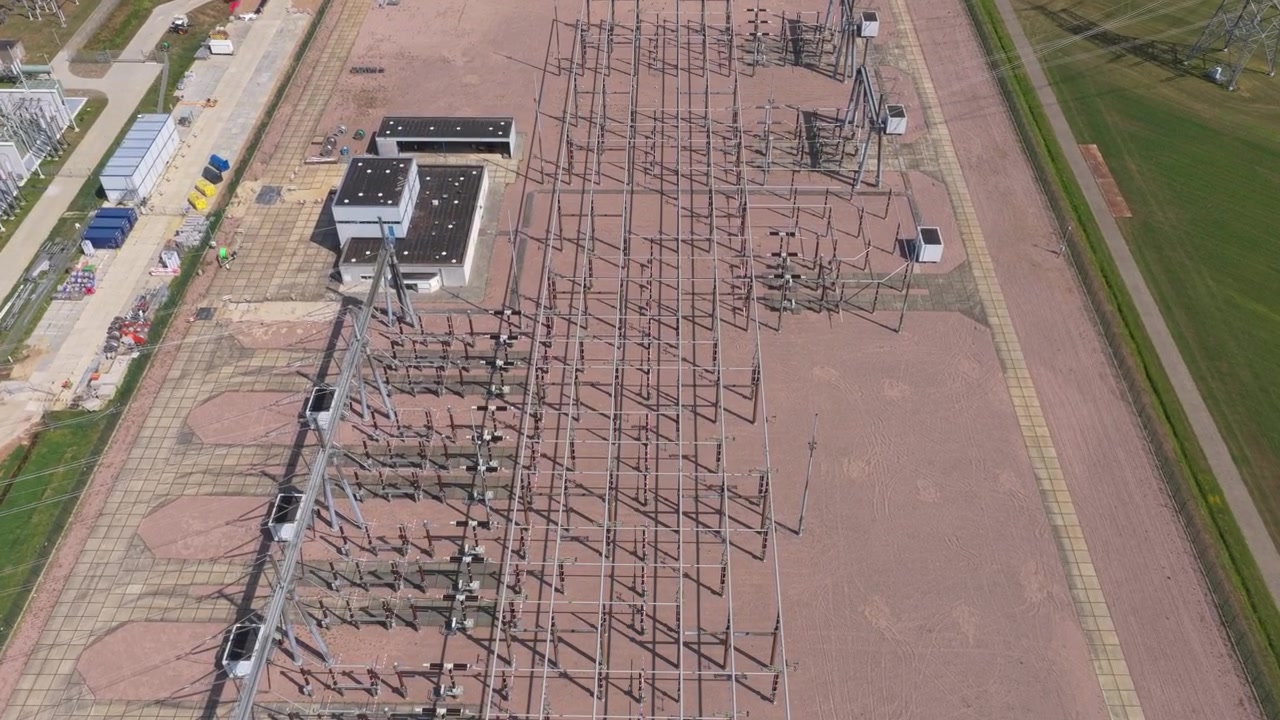 Luftfoto fra stor højde, der viser konstruktionen og udvidelsen af en elektrisk transformerstation med højspændingsmaster og infrastruktur.