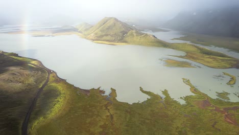 Green-mountains-and-lake-against-cloudy-sky