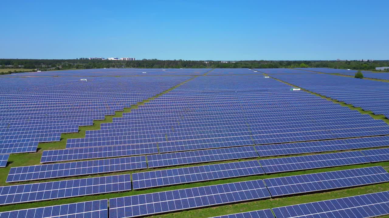 Rows of photovoltaic solar panels are absorbing the sun in a large power station under a clear blue sky. Nice aerial view flight fly reverse drone