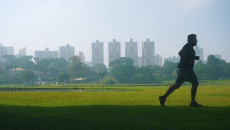 Silueta-De-Un-Joven-Corriendo-En-El-Parque-A-Cámara-Lenta-Con-Un-Fondo-Brumoso