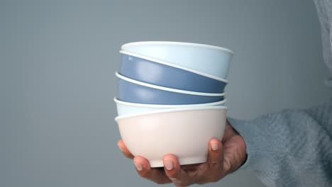 person holding stacked colorful bowls