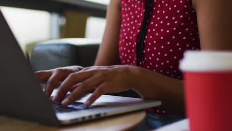 Frau-Mit-Gemischter-Abstammung-Erledigt-Papierkram-Und-Trinkt-Kaffee-Mit-Einem-Laptop-Im-Büro