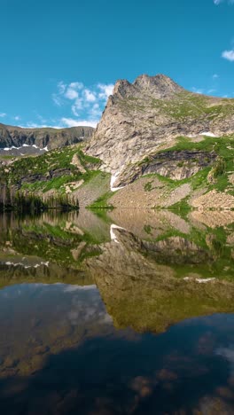 vertical timelapse, pristine alpine lake reflection of mountain peak and clouds. lower sand creek lake, wet mountains range, colorado usa