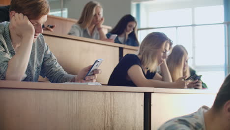 grupo multiétnico de estudiantes que utilizan teléfonos inteligentes durante la conferencia. jóvenes que utilizan las redes sociales mientras estudian en la universidad