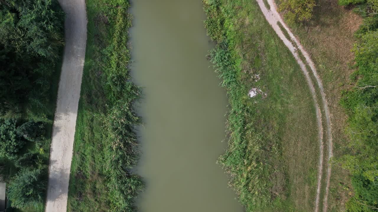 Tilt-down aerial shot of the belt canal in Dömsöd, Hungary, revealing a small rural bridge and surrounding greenery from a top-down perspective