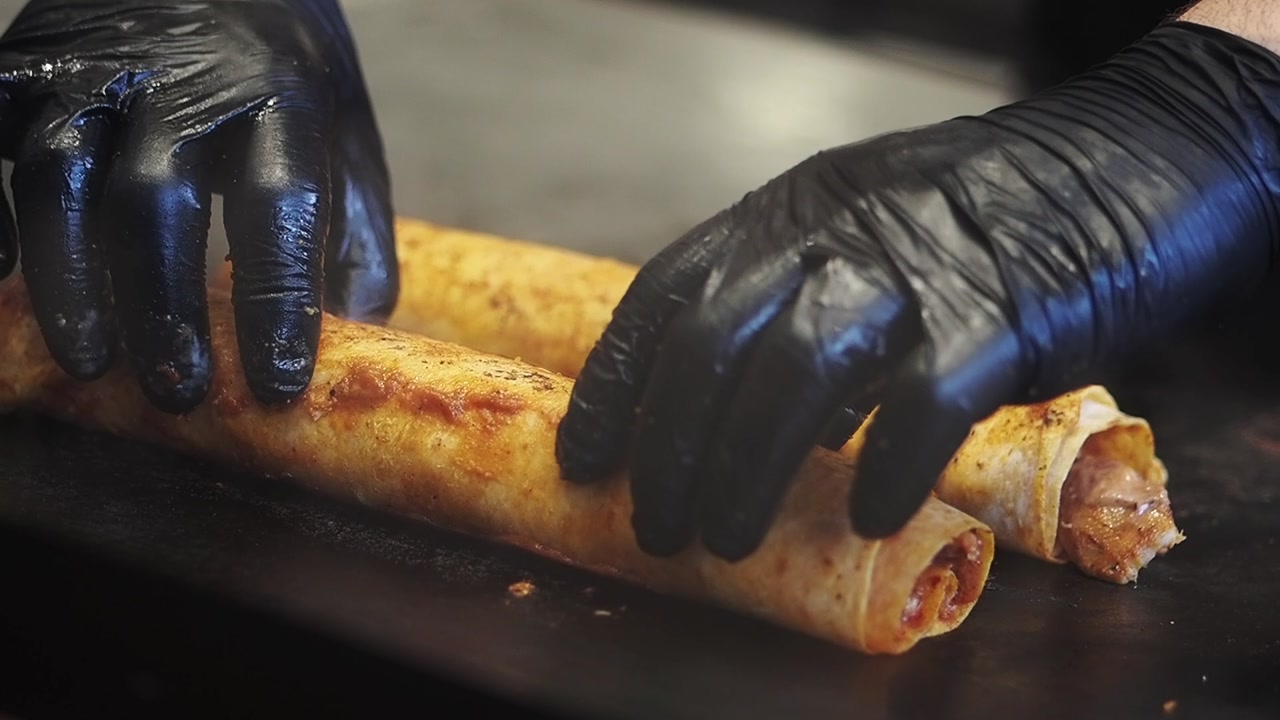 Chef's Hands Turning Delicious Wraps on a Hot Grill