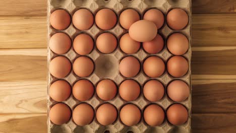 the eggs appear and disappear from the cardboard tray for the eggs on the wooden table - stop motion.