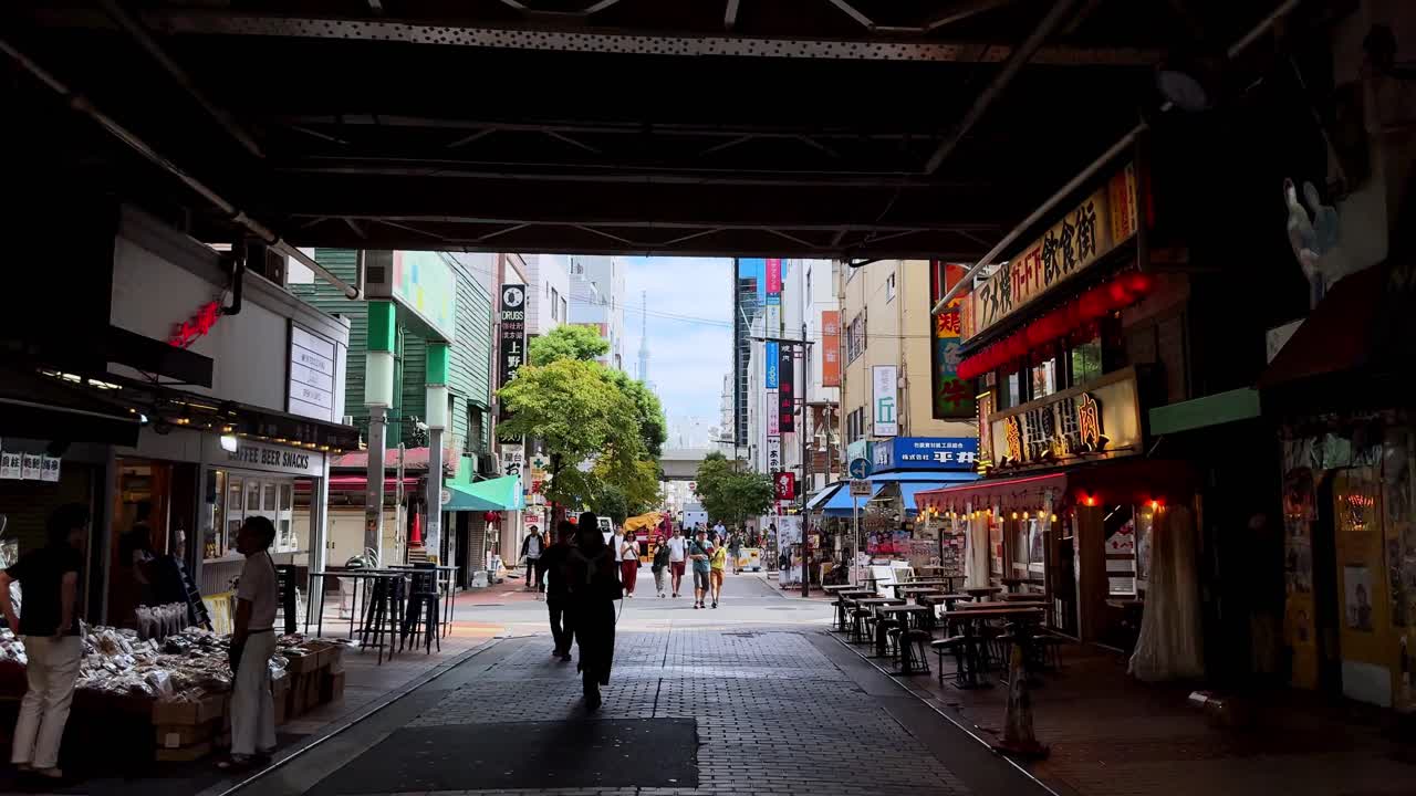 A street under a bridge in a quiet city alley with pedestrians and shops during the day