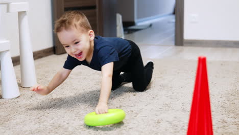 energetic caucasian toddler plying cheerfully in his room. happy kid crawls by the floor with a toy.