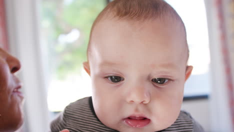 Baby-Grandson-Looking-Over-Grandmothers-Shoulder-As-She-Cuddles-Him