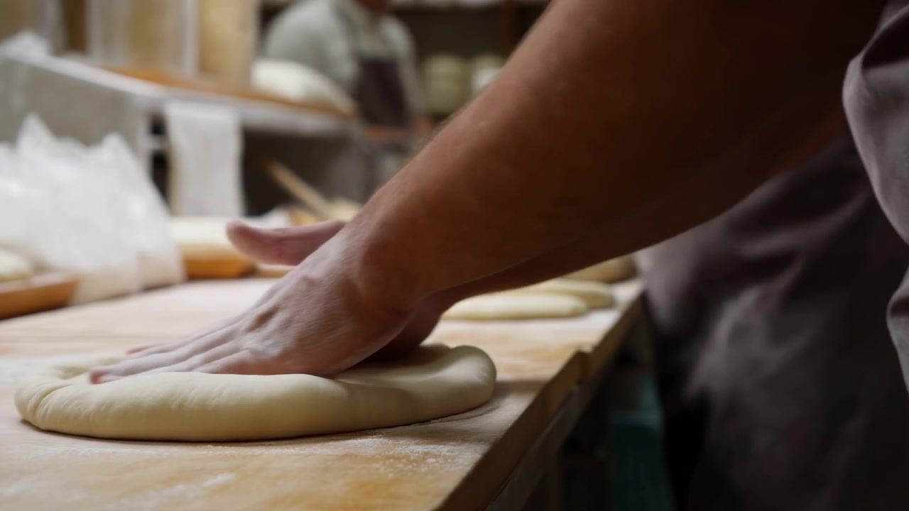 Artisan Baker Kneading Dough On Bench, Closeup Of Flourdusted Hands Pressing And Folding Soft Dough In Busy