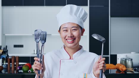 smiling chef holding utensils in a modern kitchen