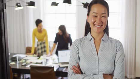 Happy-asian-businesswoman-standing-in-office-and-looking-at-camera