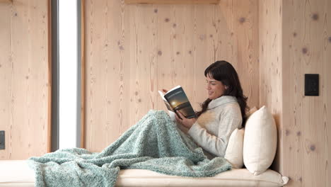 relaxing at home, woman reading book under cozy blanket, enjoying leisure time, copy space