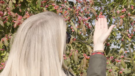 woman with blond hair near a berry tree