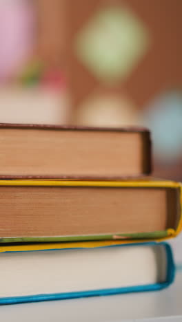 little girl hands put pile of books on white desk in classroom closeup. diligent schoolgirl prepares textbooks for lesson sitting at table at home