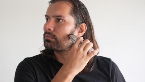 hombre latino recortando barba y bigote con afeitadora eléctrica, cepillo de afeitar