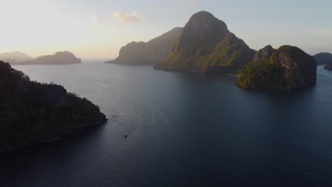 Vista-Aérea-Mientras-El-Sol-Se-Pone-En-El-Horizonte-Del-Océano-Con-Islas-De-Acantilados-Escarpados-En-Asia