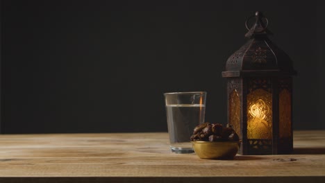 Toma-Estacionaria-De-Agua-De-Linterna-Y-Dátiles-En-Una-Mesa-Para-El-Ramadán