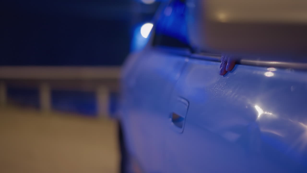 손으로 여는 밤색 자동차 문, 불안한 네온 조명, 손잡이와 움푹 들어간 패널 클로즈업, 배경에 보이는 도시 다리 조명, 청바지와 재킷을 입고 차 안으로 손을 뻗는 운전자, 긴장감 넘치는 영화의 한 장면 같아요.