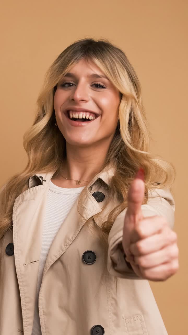 Contented stylish transgender woman looking at camera and showing thumbs up