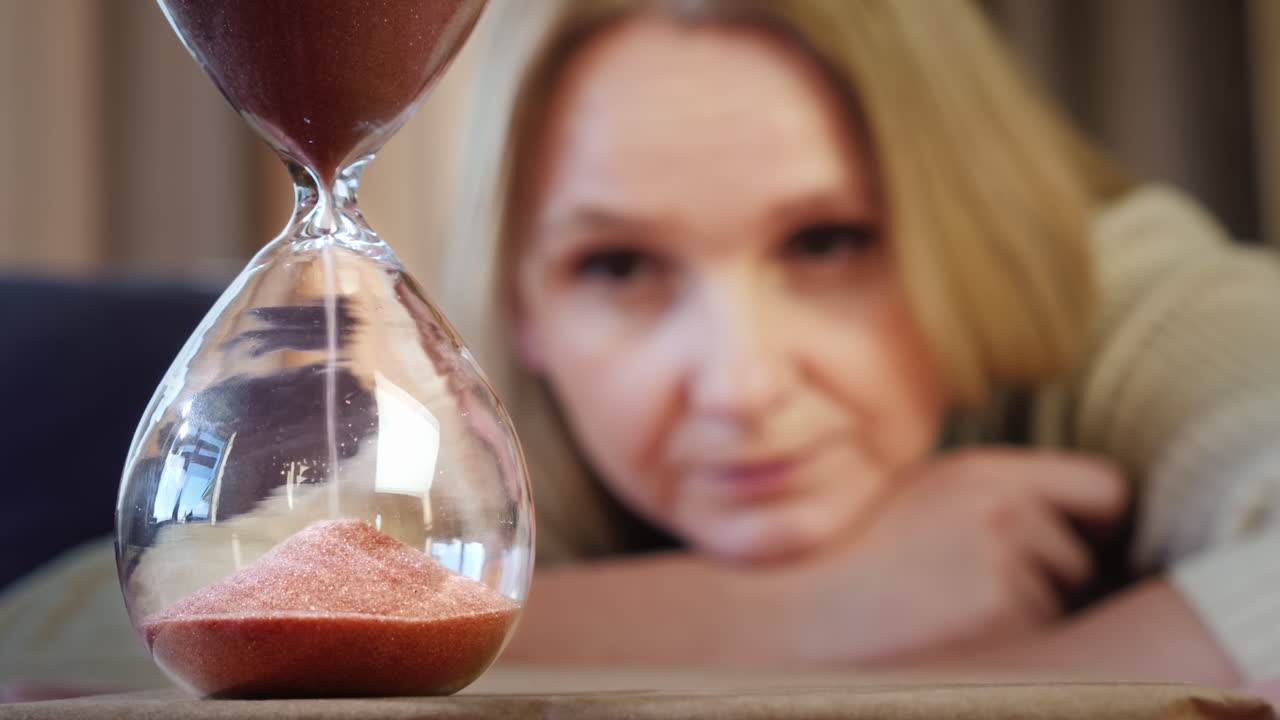 женщина смотрит на песочные часы 2