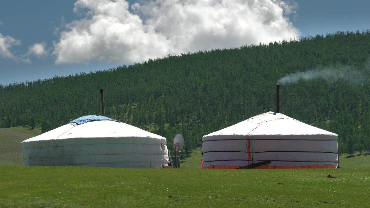 Traditionella mongoliska jurtor i ett grönt bergslandskap