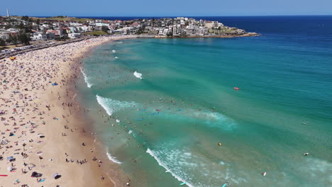 panning drone shot of bondi beach, highlighting sunbathers, swimmers, and surfers along the famous australian coast. aerial footage.