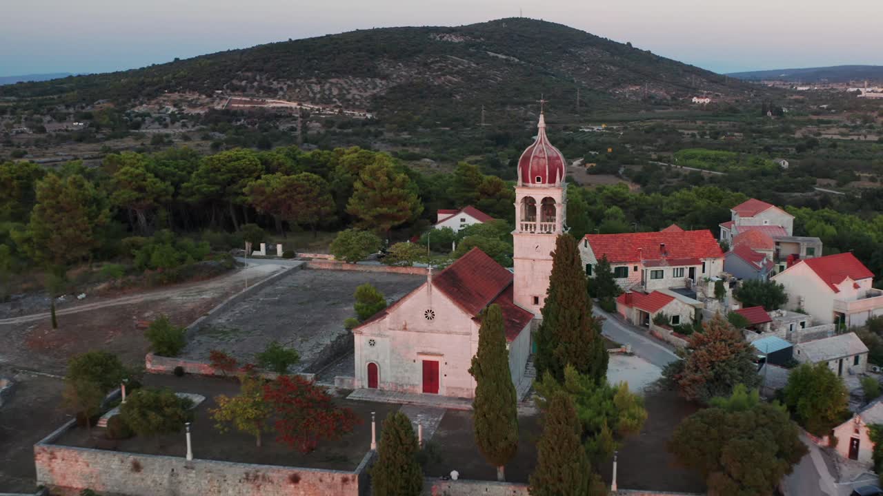 un avión no tripulado retrocedido revela la iglesia y el campanario en donji humac, un pequeño pueblo en la isla de brač, croacia.