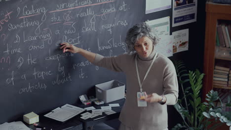 maestra señalando a la pizarra, explicando la gramática inglesa durante la clase