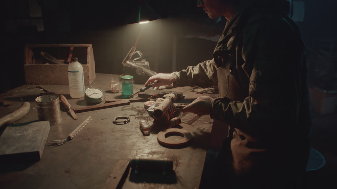 A bombmaker assembles a bomb in his workshop at night
