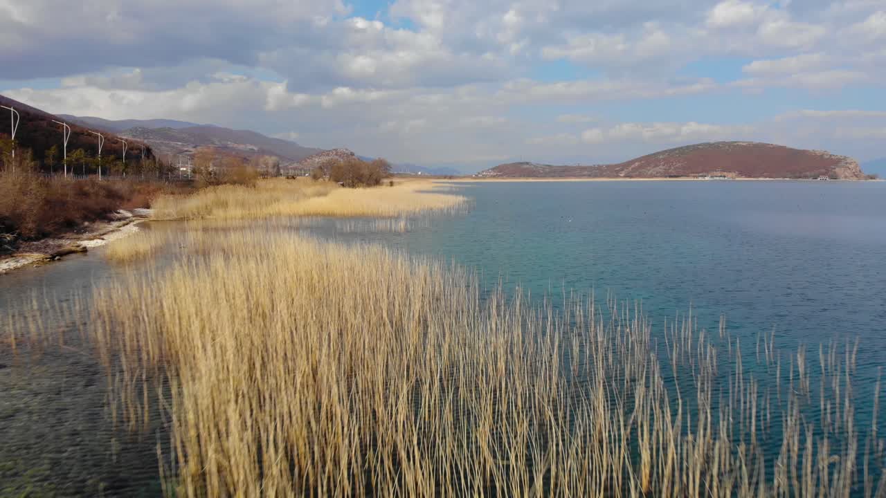 paisaje del lago paraíso, guijarros en la orilla y cañas secas lavadas por agua turquesa