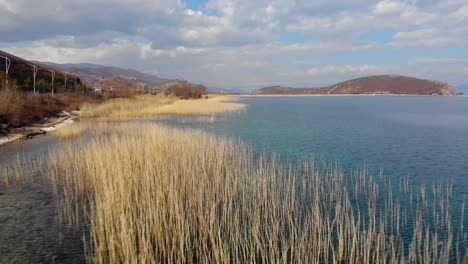 paradise lake landscape, pebbles on shore and dry reeds washed by turquoise water