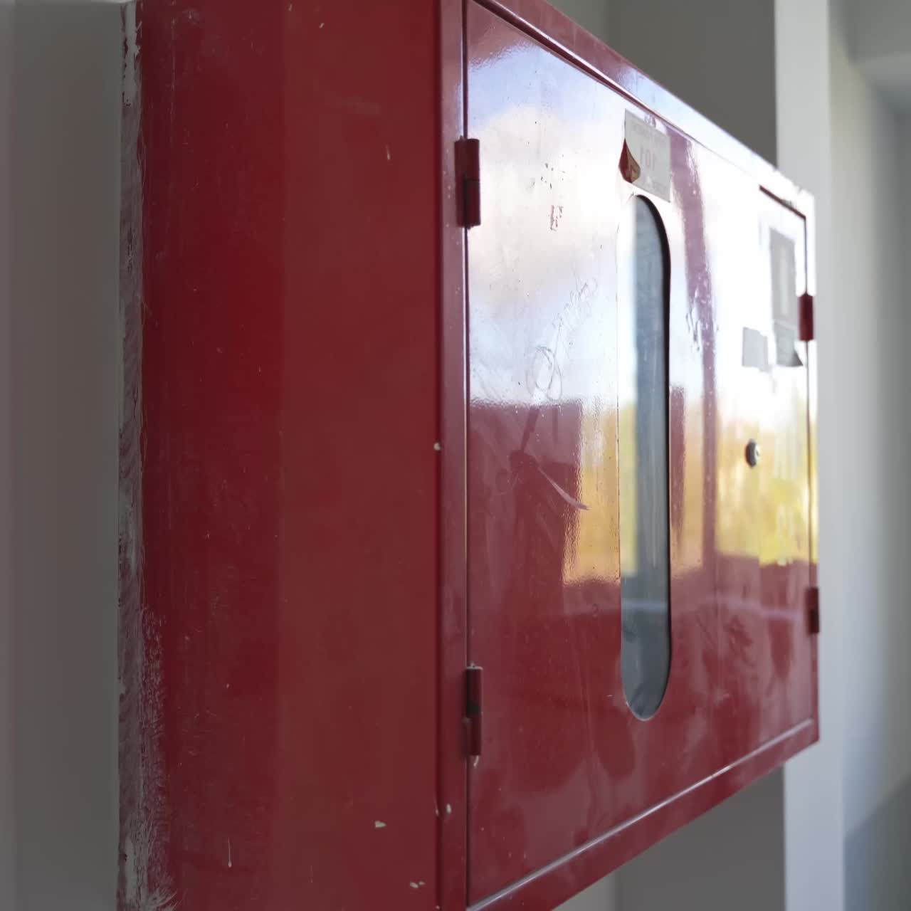 Red locker box with firefighting equipment inside. White interior of newly-constructed office premises