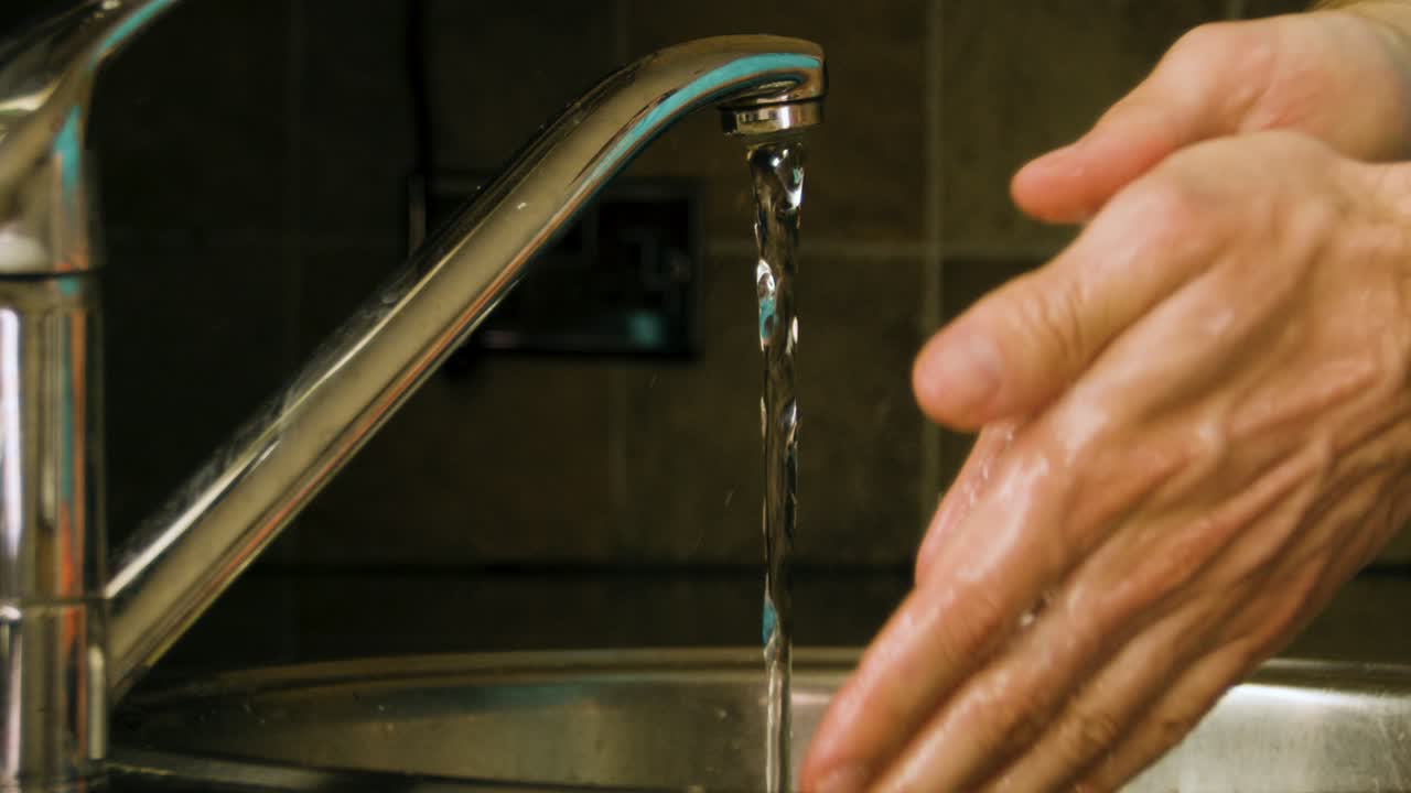 lavarse las manos jabonosas y enjuagarse con agua en un fregadero de cocina casero a cámara lenta