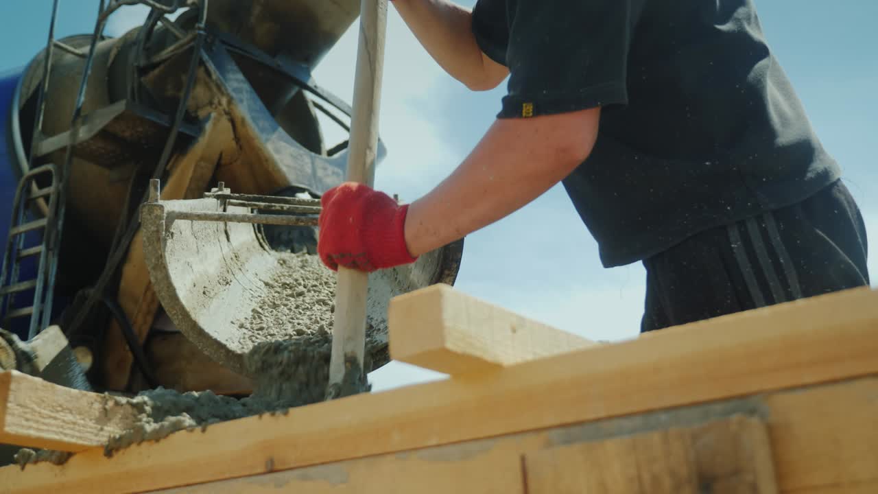 el trabajador toma el hormigón de una mezcladora industrial, trabaja como una pala. trabajo manual pesado en el sitio de construcción. tiro de ángulo bajo