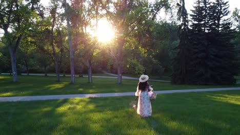 Black-Woman-with-basket-walking-in-park-sun-bursting-drone-followed