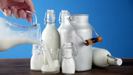 male hand pouring milk from a jug into a glass.